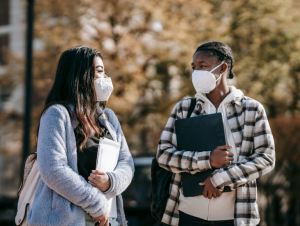 two masked students talking on campus