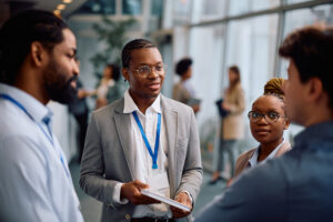 African American businessman talking to his colleagues in hallway of a convention center.